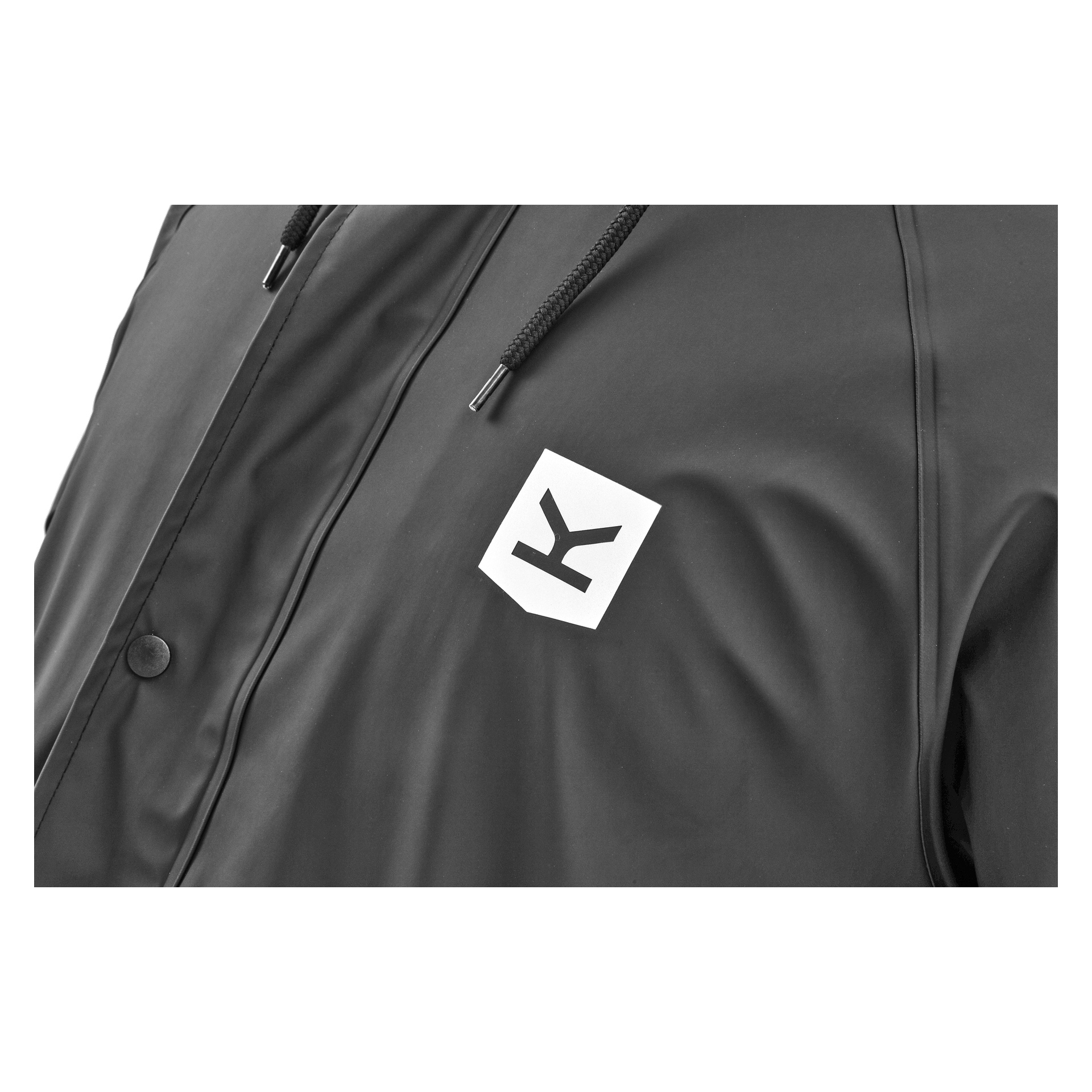 Nahaufnahme der Kayoba Outdoor Men's Visby Regenjacke in Schwarz mit Fleecefutter. Die Jacke zeigt ein weißes Patch mit einem markanten schwarzen Buchstaben K auf der linken Brust und enthält schwarze Kordeln und Druckknöpfe.