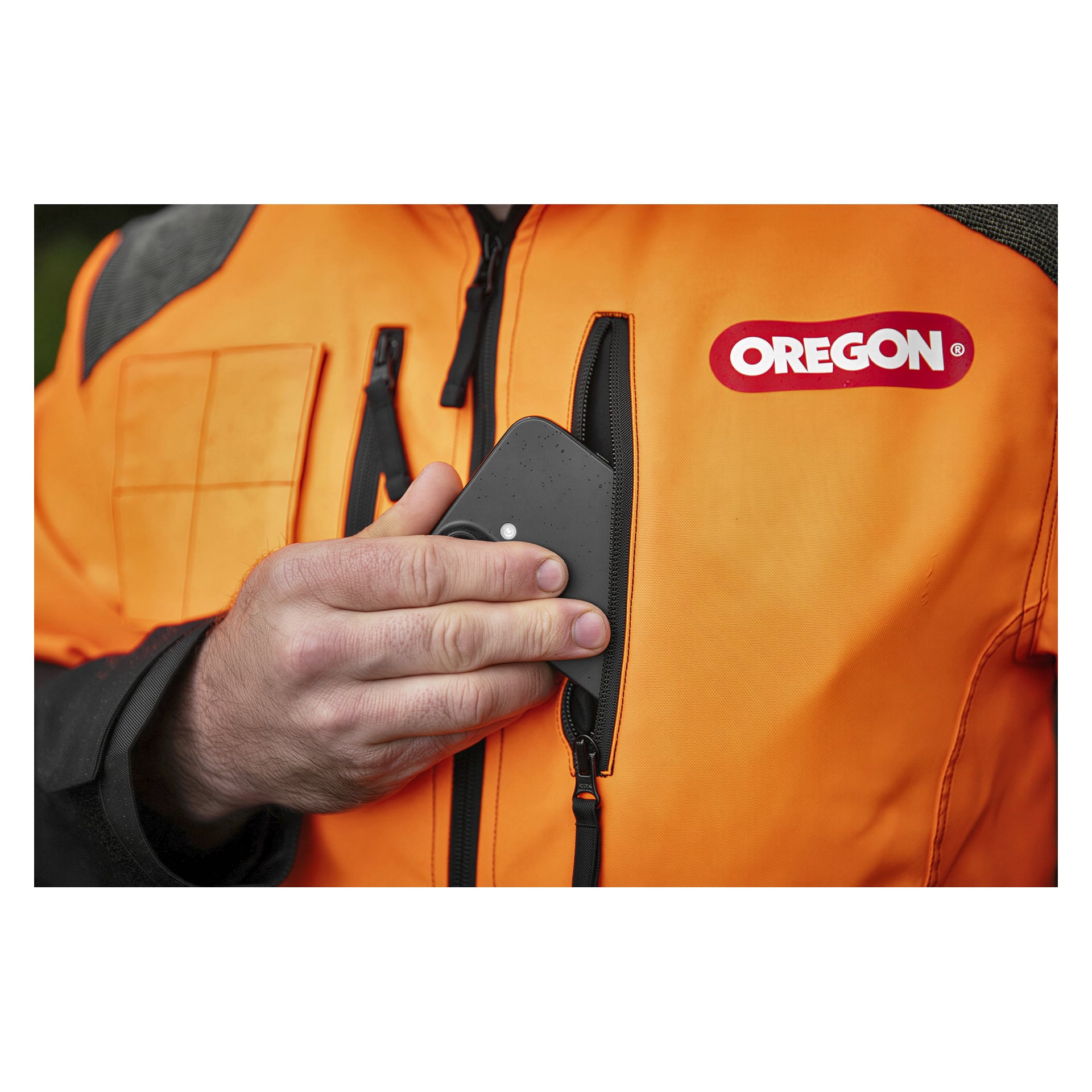 En hand som placerar en smartphone i bröstfickan på en orange skyddsjacka från Oregon Protect Plus.