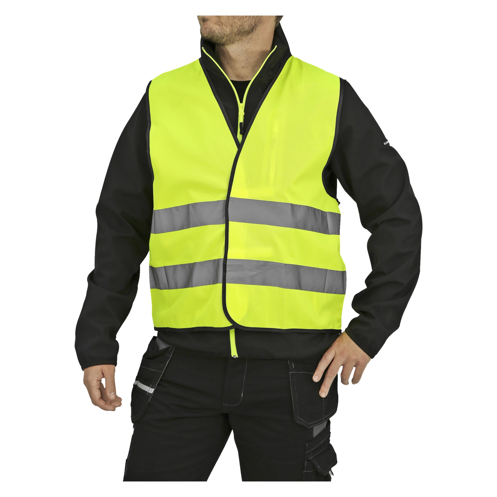 En person kledd i en høyt synlig gul Bluewear reflekterende tabard med to horisontale reflekterende striper, båret over en svart jakke og svarte bukser. Den ene hånden hviler på hoften mens den andre henger langs siden. Ansiktet deres er delvis beskåret ut av bildet.