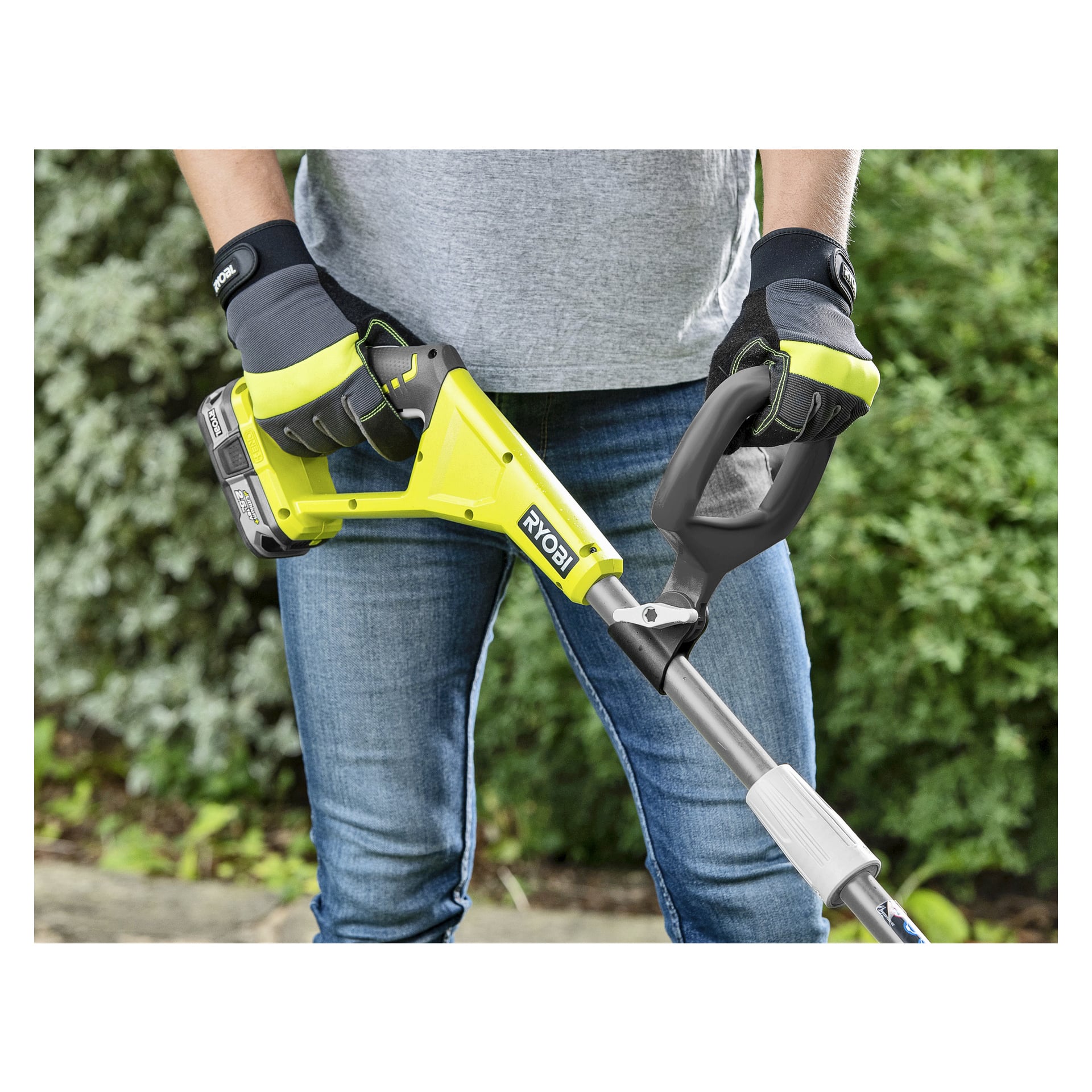 Noen med hansker og jeans bruker en gul Ryobi One+ Edge-trimmer RY18EGA-0 ute, omgitt av grønne planter.