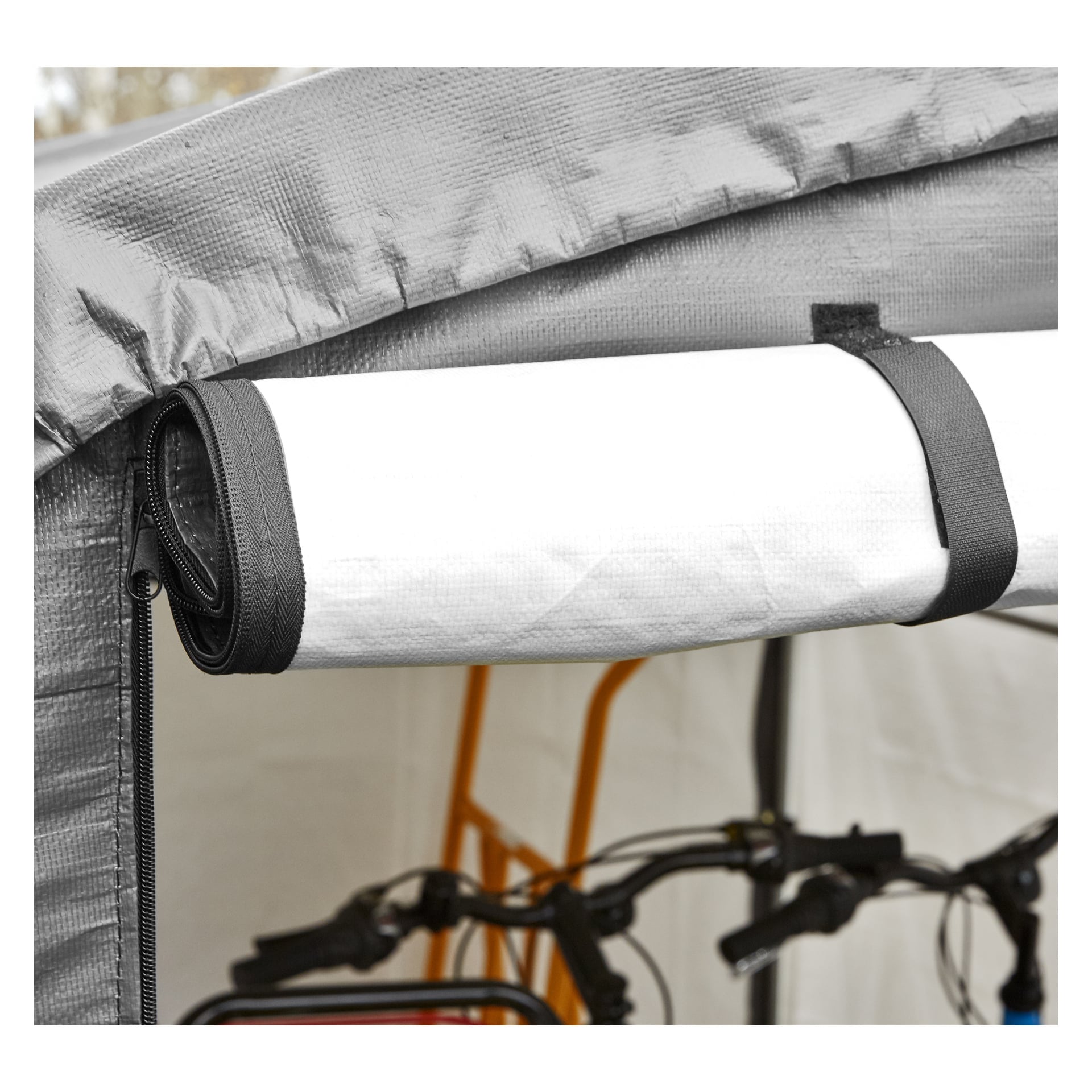 Ett grått och vitt Hamron Garage Tältet har en hoprullad panel fastsatt med två svarta remmar, medan en del av en cykel och en orange ram syns i bakgrunden.