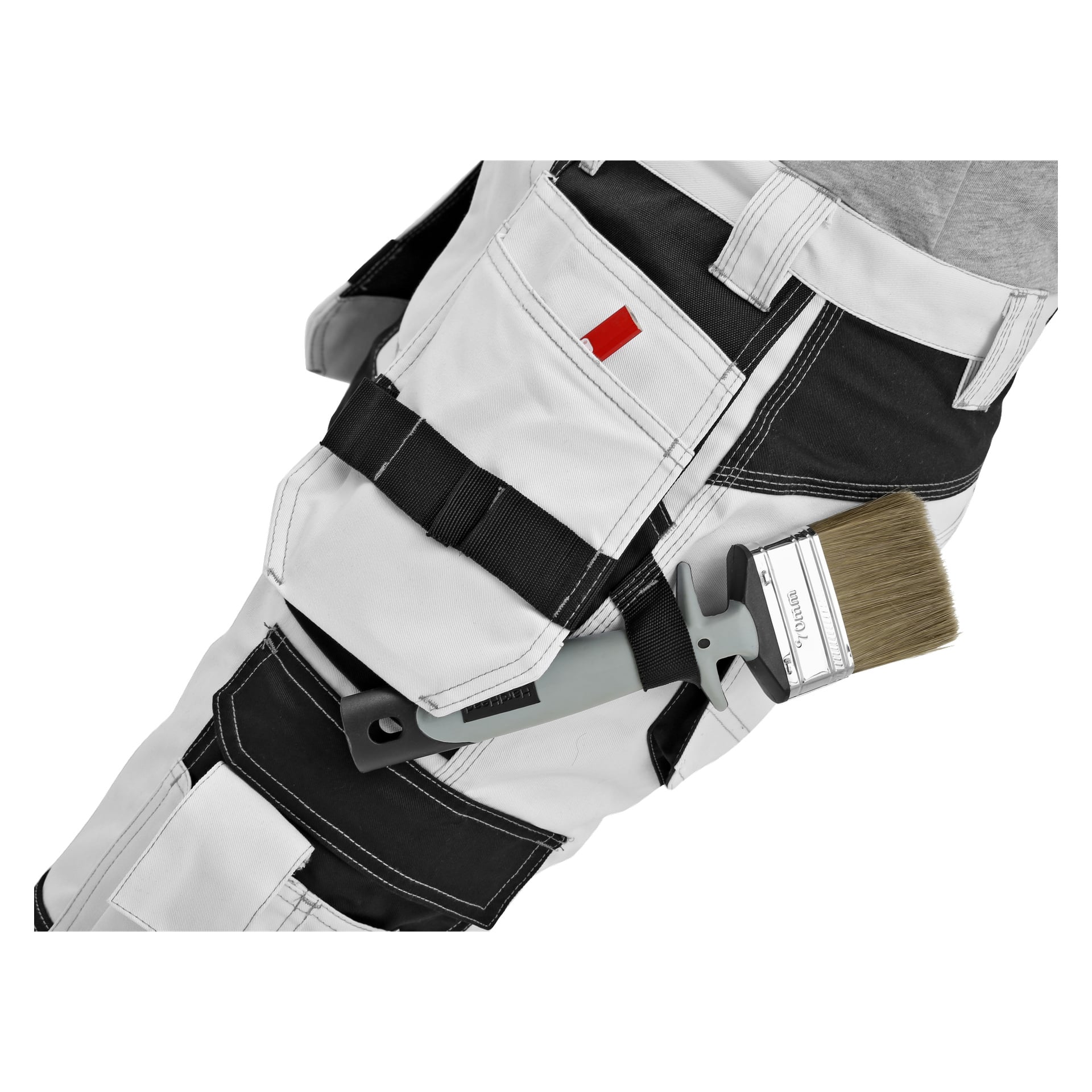 Zbliżenie osoby ubranej w męskie spodnie malarskie Bluewear, białe z czarnymi detalami i kilkoma kieszeniami. Pędzel trzymany jest w pętli na jednej z kieszeni.