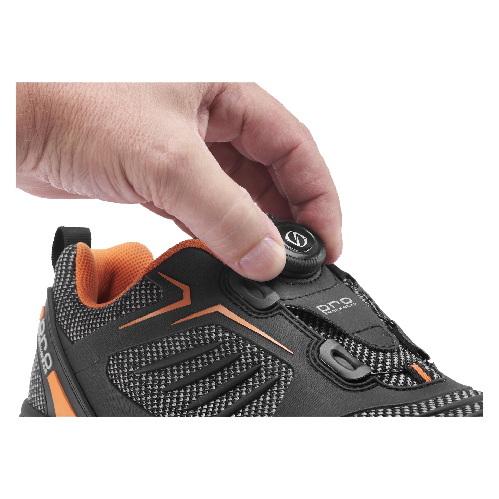 En hand vrider på snörningsratten på Bluewear Pro Workwear Madison säkerhetsskor, som visar en svart och orange färgskala med en texturerad yta, starkt orange innerfoder och en "pro"-etikett bredvid skosnörena.