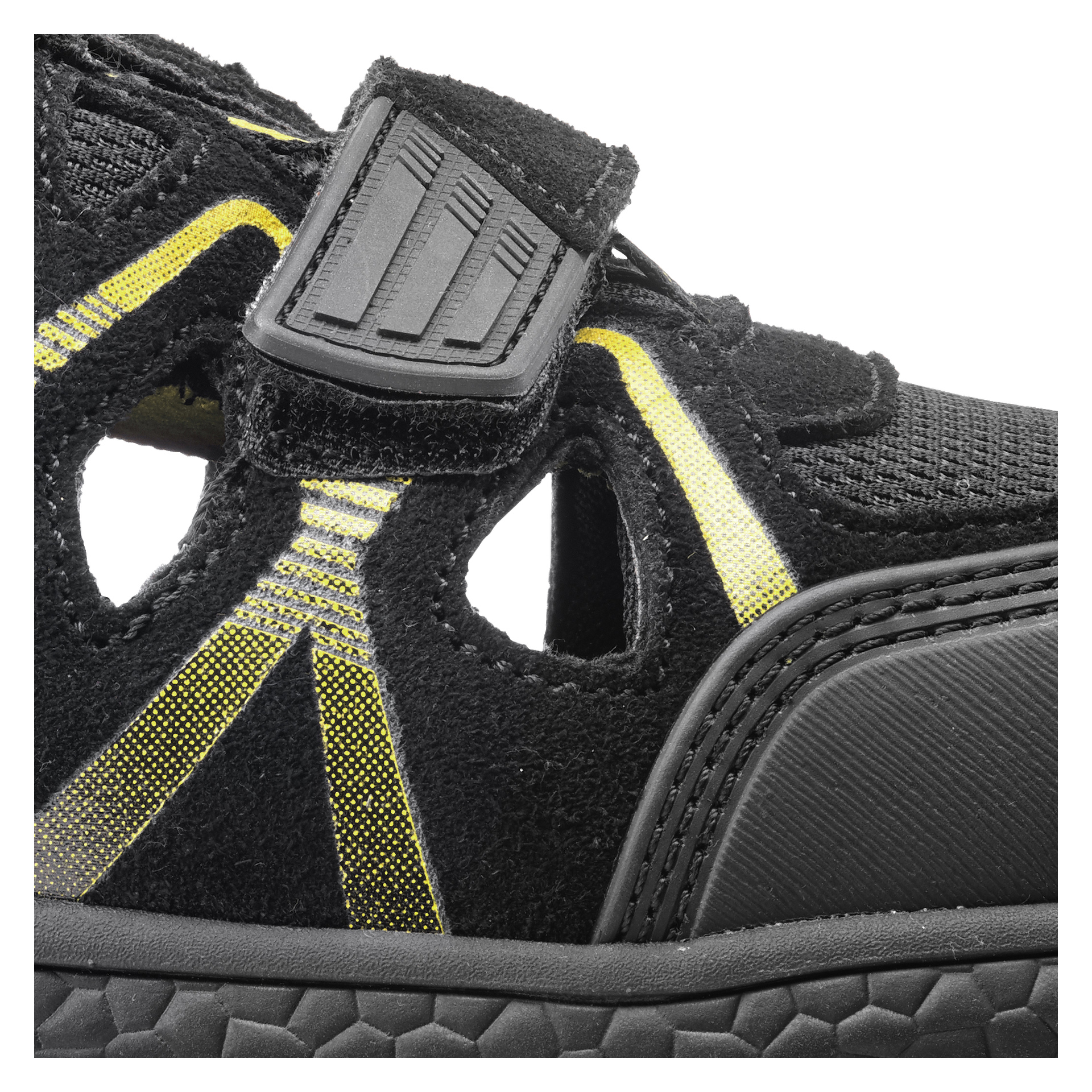 Detaljerad närbild av Bluewear Safety Hampton-sandaler i svart med gula detaljer, som visar utskurna paneler, ett mönstrat kardborreband och en robust gummisula med tydlig textur. Konstruktionen kombinerar nättyg med syntetiska överlägg för hållbarhet.