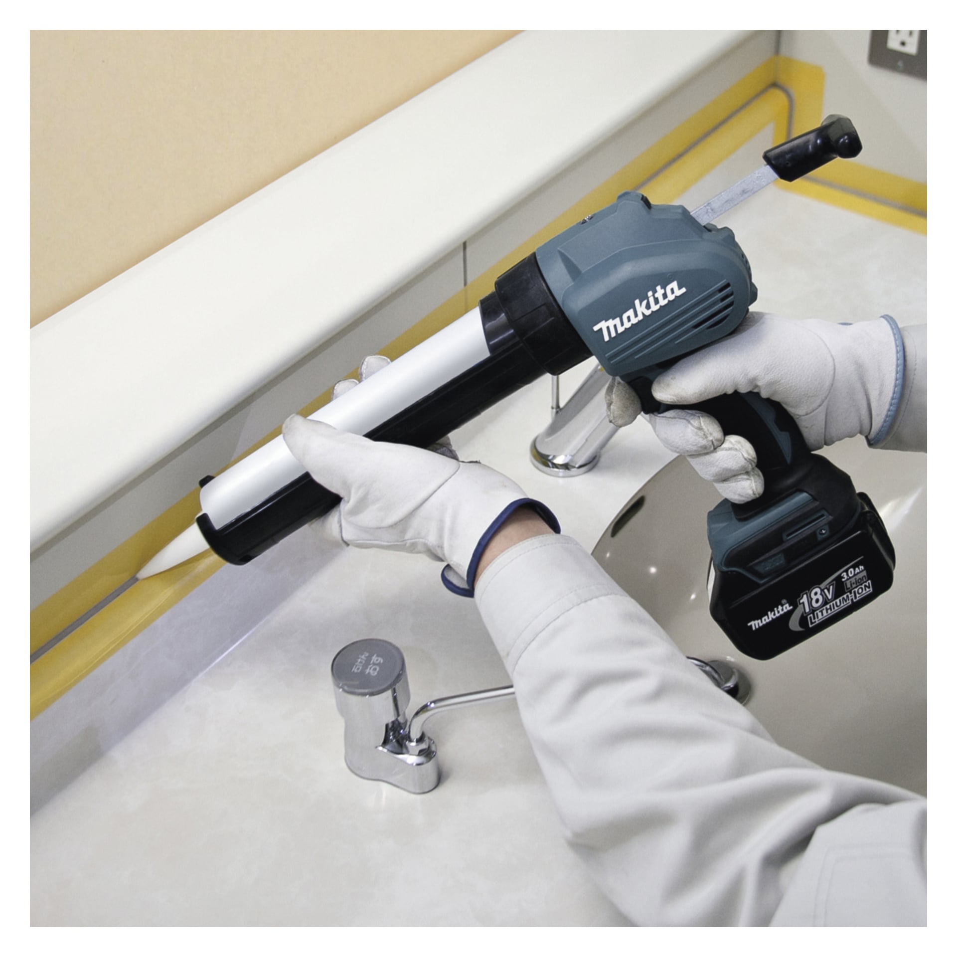 En person med handske använder en Makita batteridriven fogmassa (DCG180Z) för att applicera tätningsmedel snyggt längs övergången mellan en badrumsdiskbänk och väggen, med gul maskeringstejp som noggrant kantar skarven för en prydlig finish.
