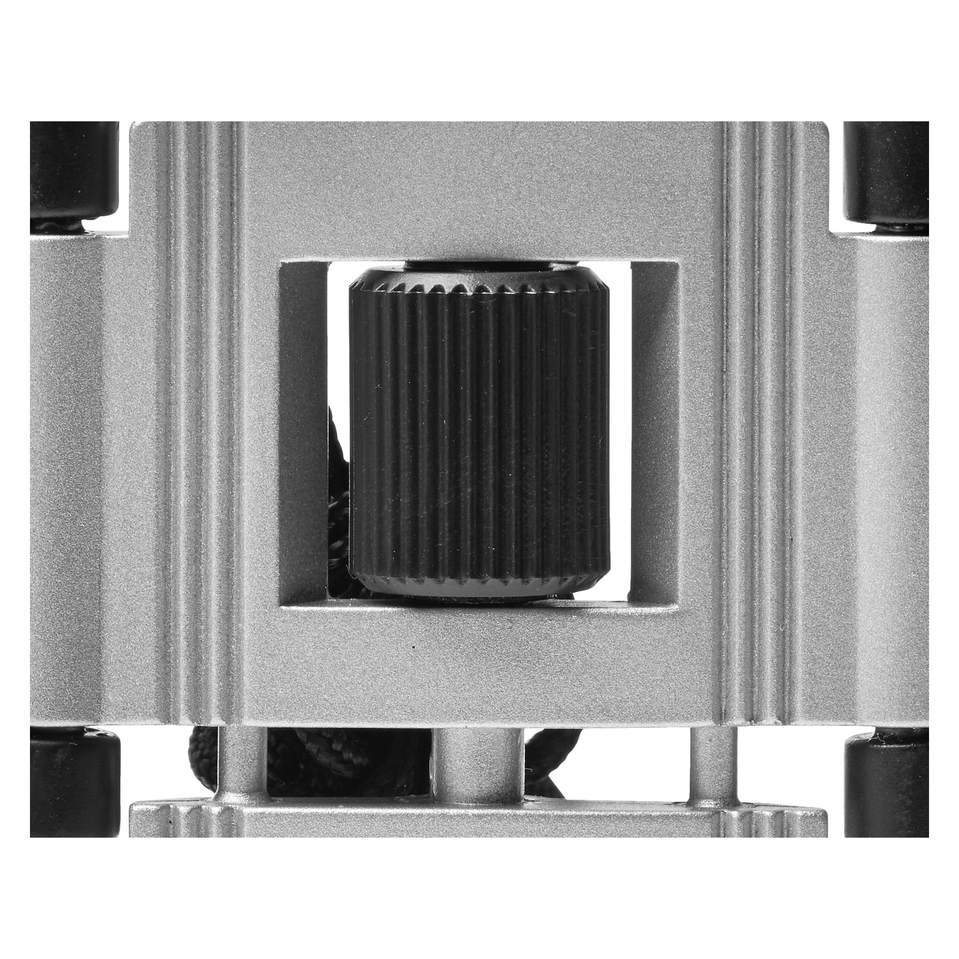 Detaljerad närbild av Kayoba Binoculars fokuseringsratt, som visar en svart, räfflad cylinder placerad i mitten av en fyrkantig silverram med skarpa, geometriska kanter.
