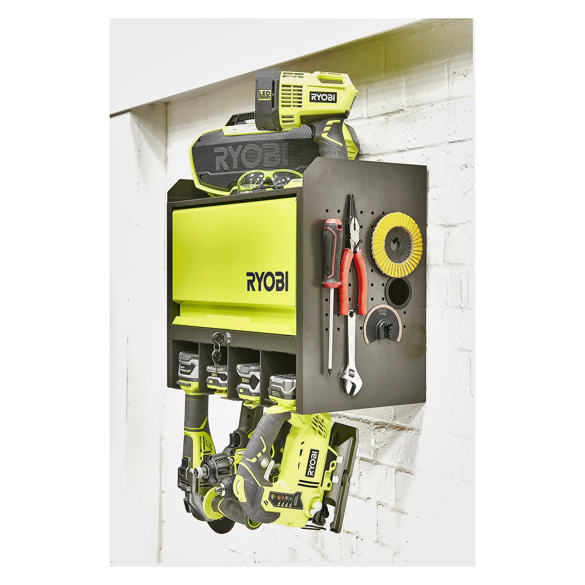 Ett Ryobi-väggskåp är organiserat med borrmaskin, drivmaskin, laddare, batteri, skiftnycklar, tång, rengöringsborste och två borrbor som är prydligt förvarade inuti.