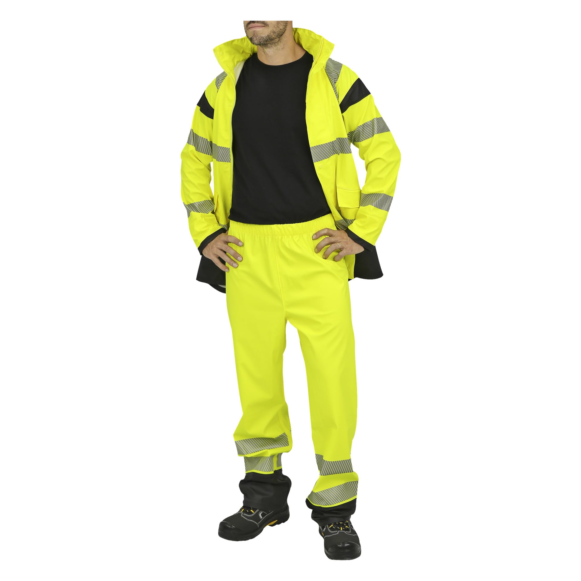 En person står med händerna på höfterna, klädd i Bluewear Hi-vis tvådelad gul regndräkt med reflekterande remsor. De bär också en svart skjorta och svarta arbetsskor. Jackan är öppen och byxorna har ett elastiskt midjeband.