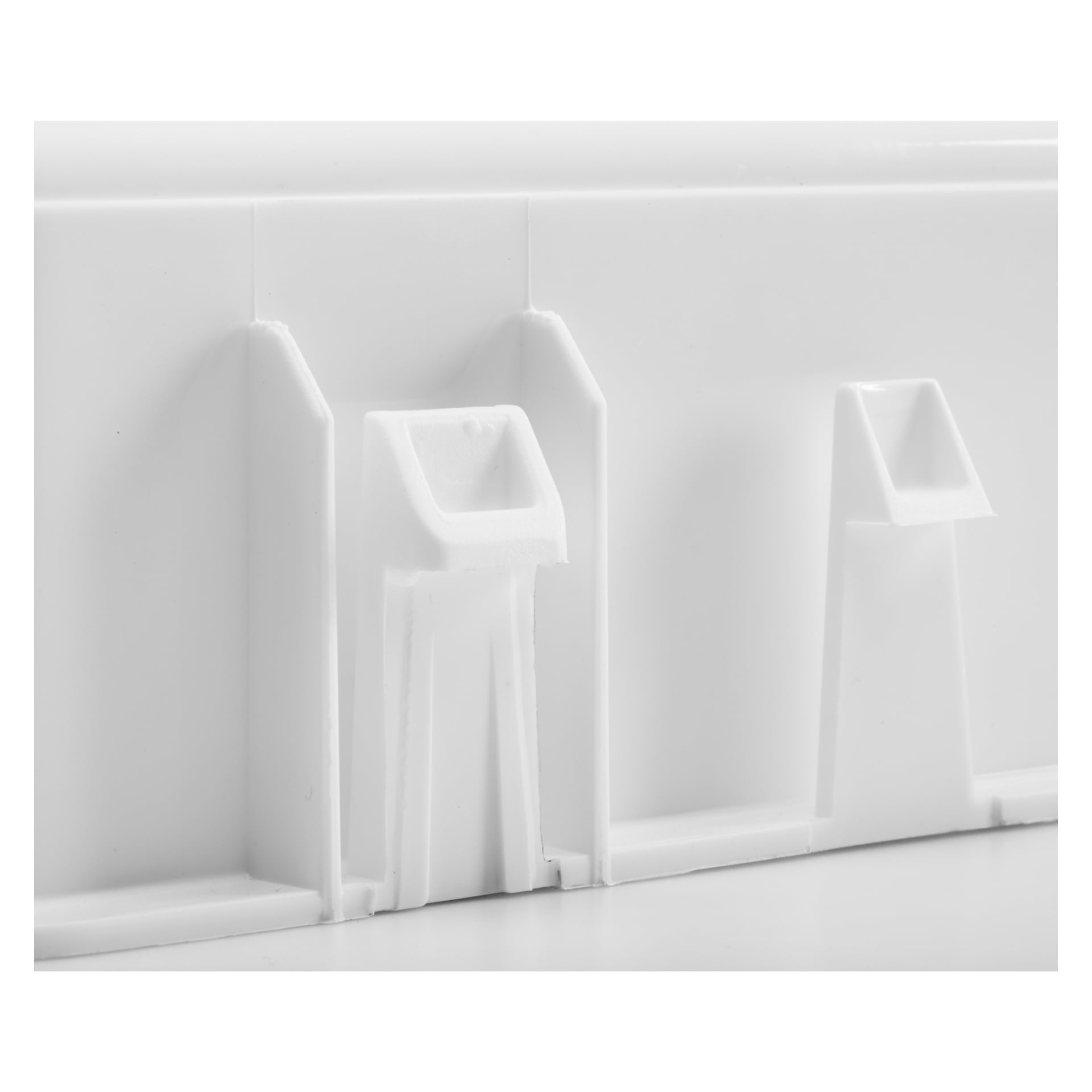 Närbild av Ventura Mounting Box, en vit plastbit med geometriska utskott och infällda utskärningar. Fokus ligger på textur och design av de formgjutna plastdetaljerna.