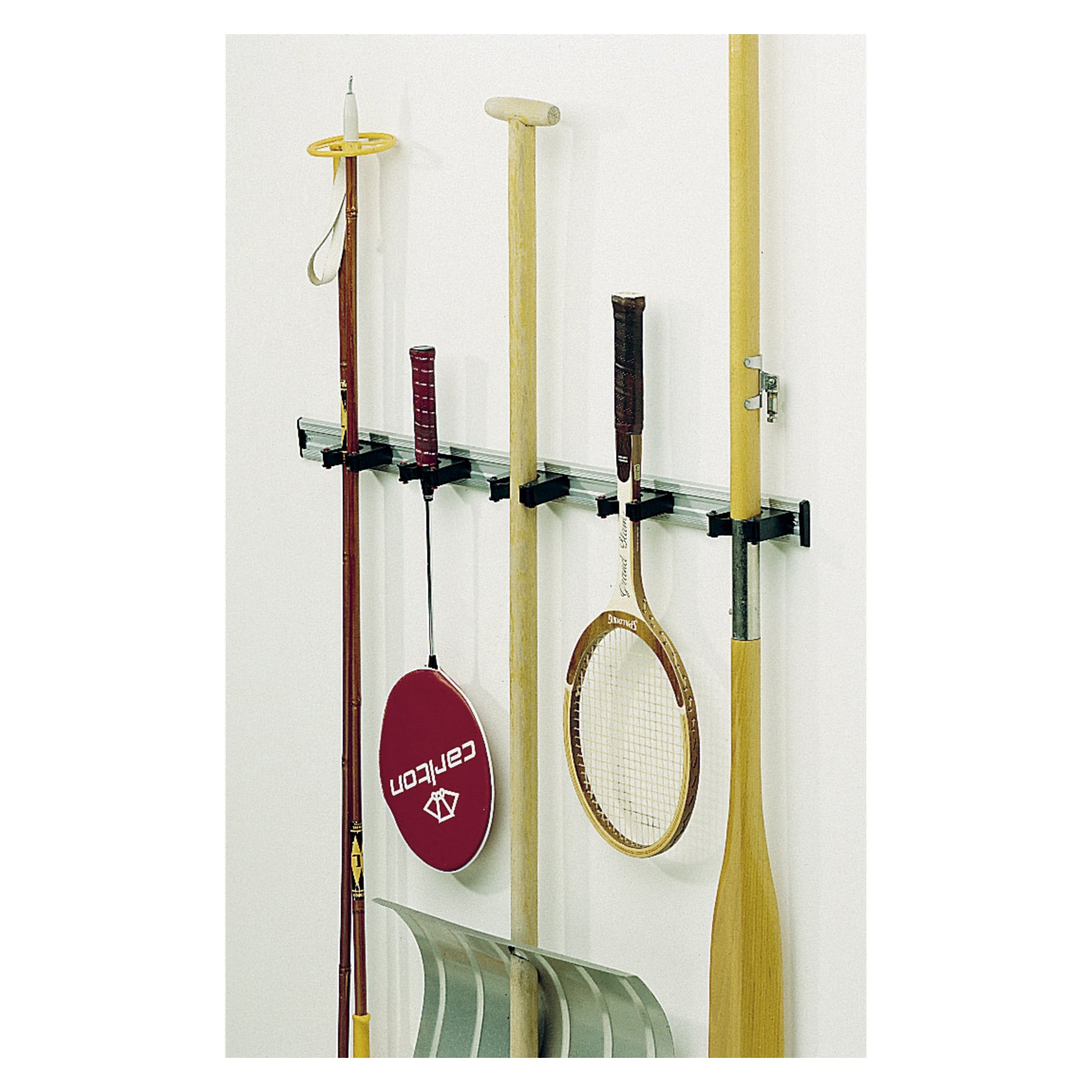 Ett Toolflex Equipment-hållerställ är monterat på väggen och visar sex föremål som hänger vertikalt: ett fiskespö, en bordtennispaddle, basebollträ, tennisracket, åra och en snöspade.
