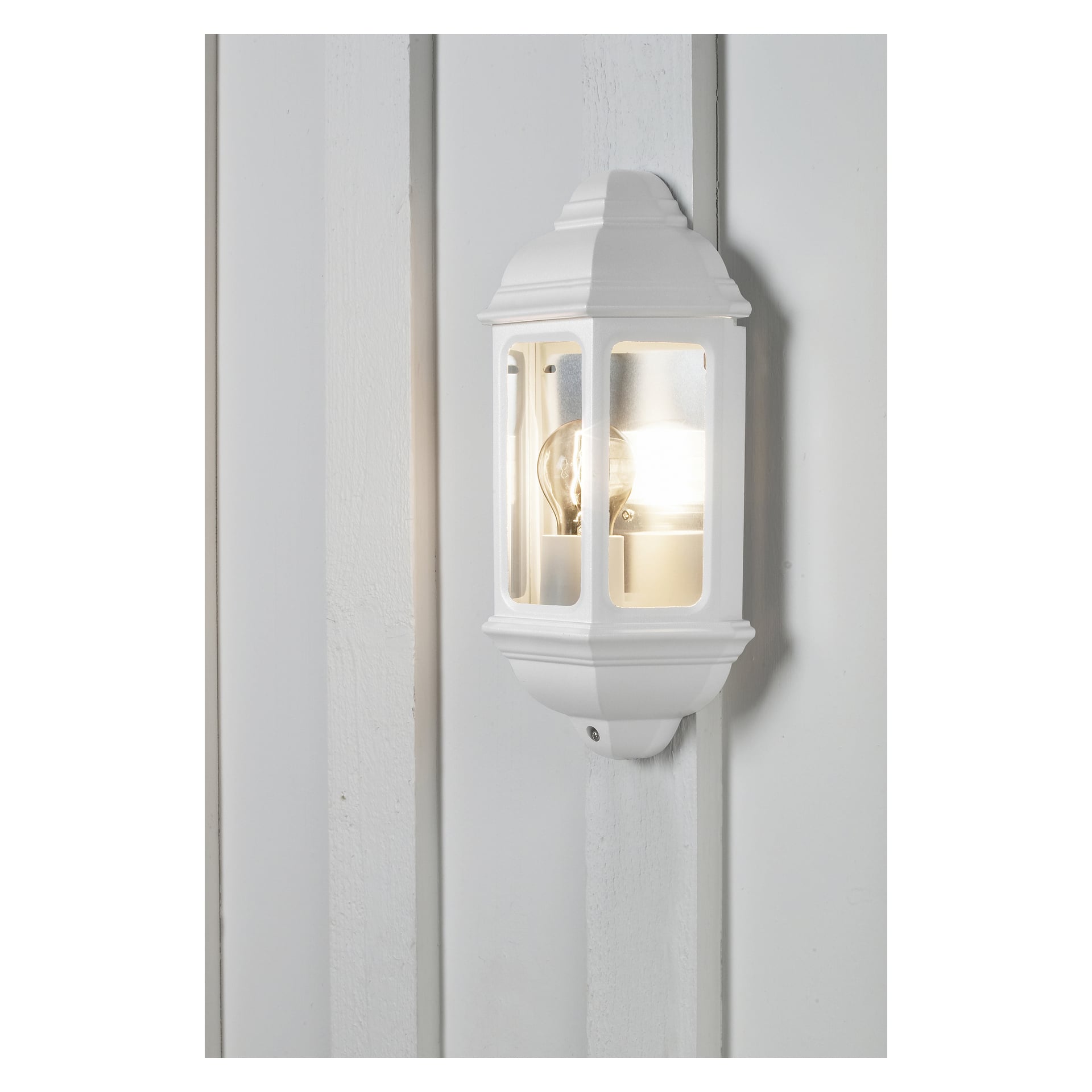 En Anslut-vägglampa med klara glaspaneler är fäst på en trävägg, med sin glödlampa tänd inuti armaturen.