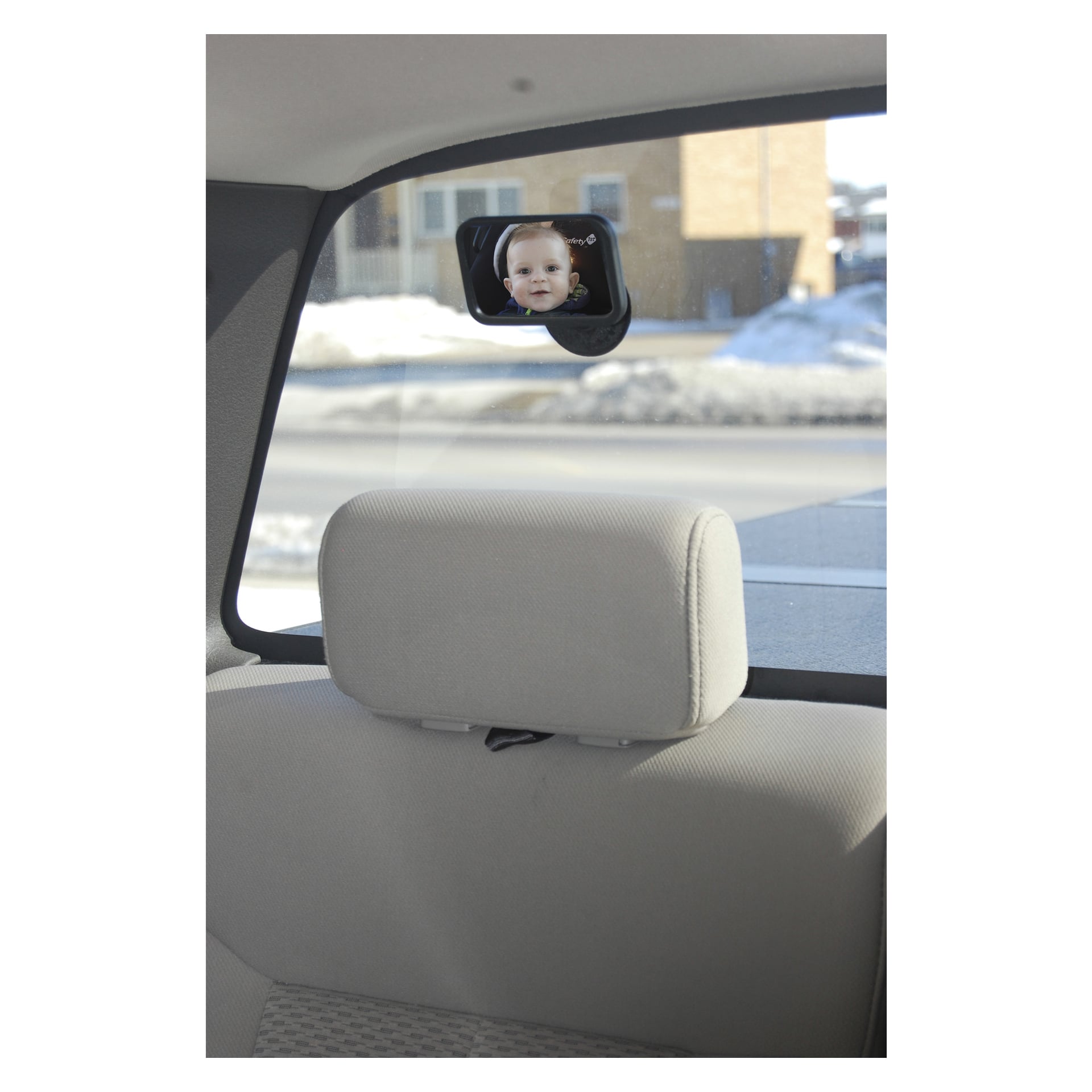 Lusterko Hamron Rear Seat Beam przymocowane do tylnej szyby samochodu odbija twarz niemowlęcia w foteliku stojącym do tyłu, a przez okno widać zaśnieżone krajobrazy i budynki.