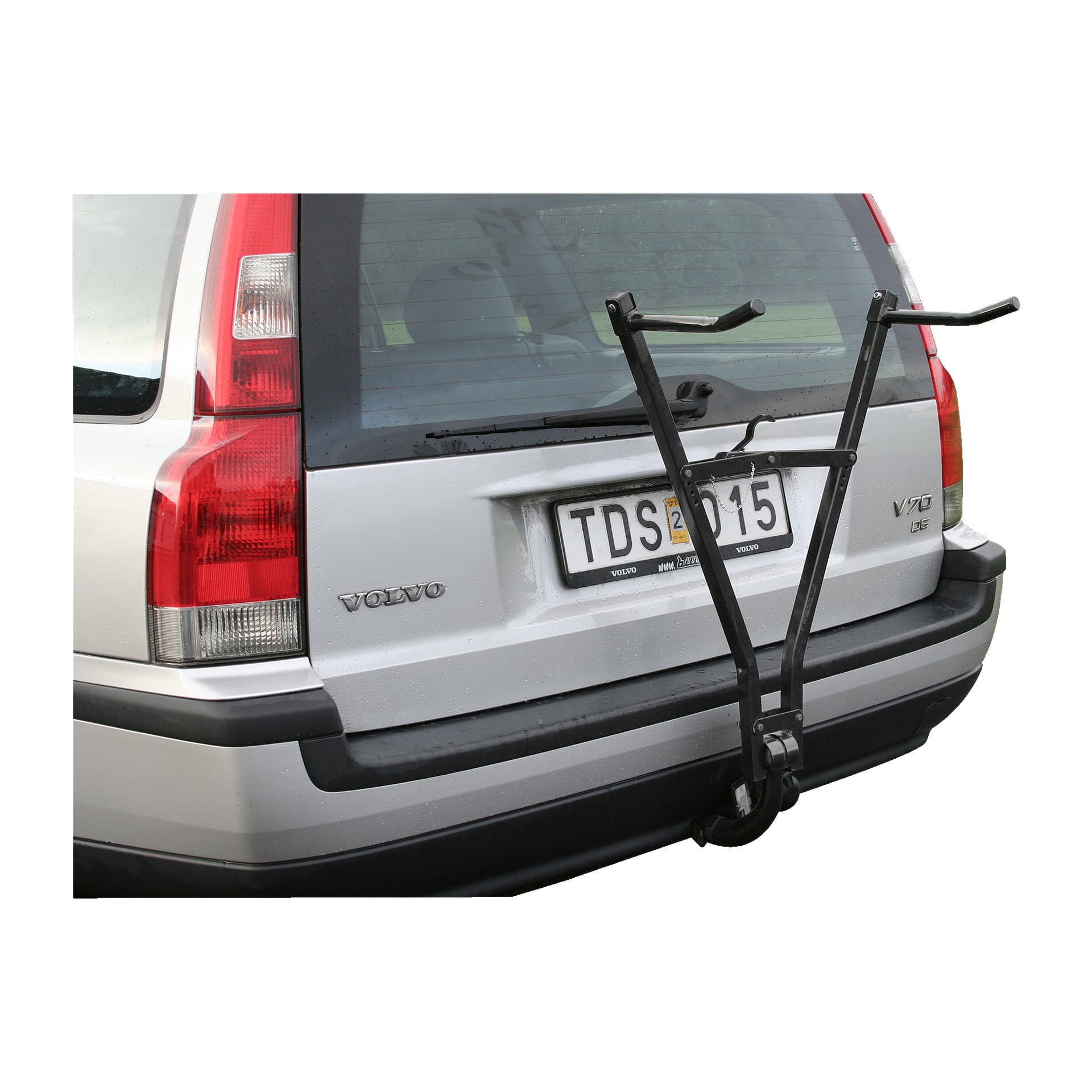 En silverfärgad Volvo V70 med en svart Hamron-bärstol monterad på bakdörren står parkerad vid en gräsyta längs gatan. Registreringsskylten kan ses, och fordonet har ett blött utseende från regn.