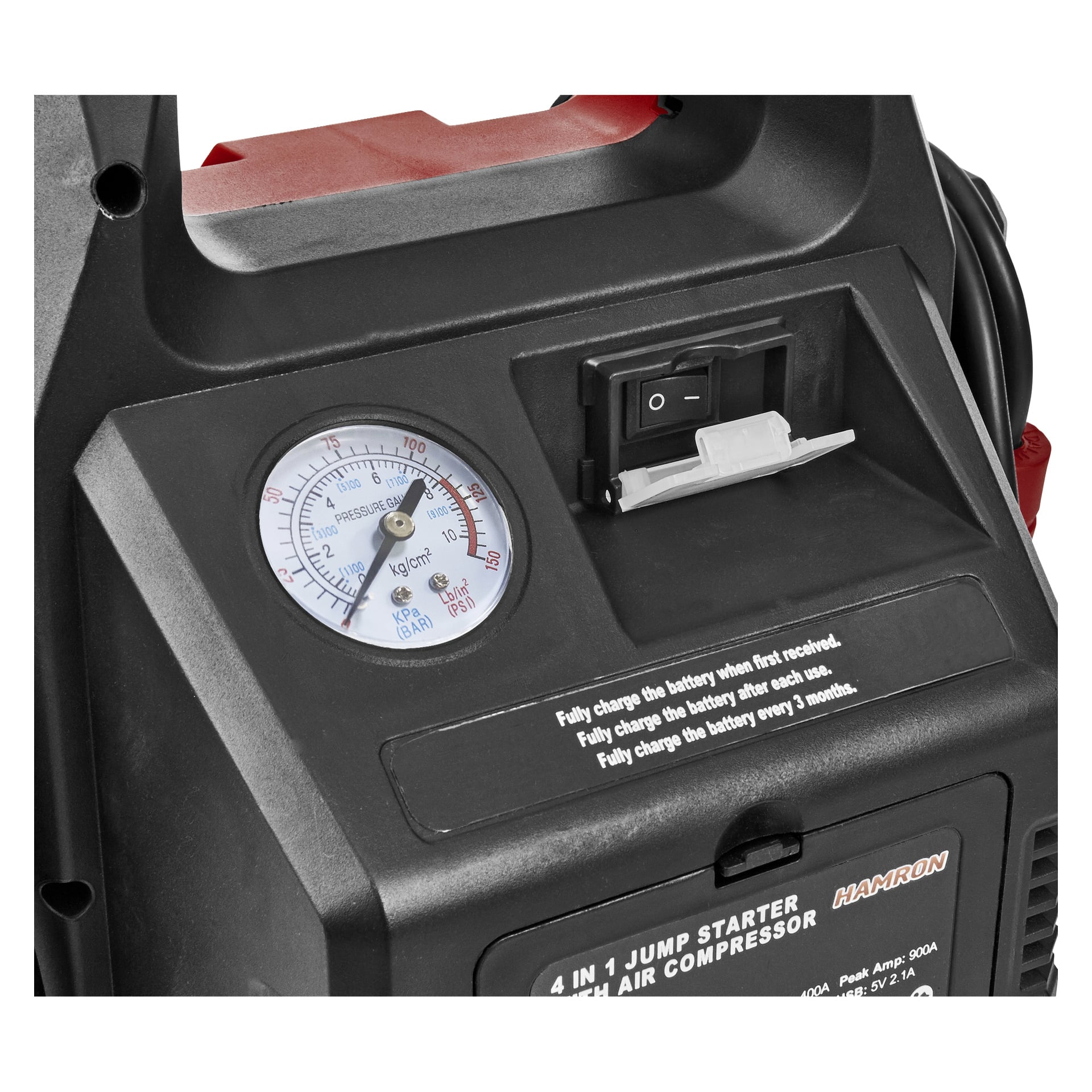 Nærbilde av Hamron Jump Starter 4-i-1 med trykkmåler, svart av/på-bryter og hvit plastflik. Det svarte dekselet viser instruksjonstekst og deler av merkeetiketten, inkludert sitater som Hamron og andre synlige instruksjoner.