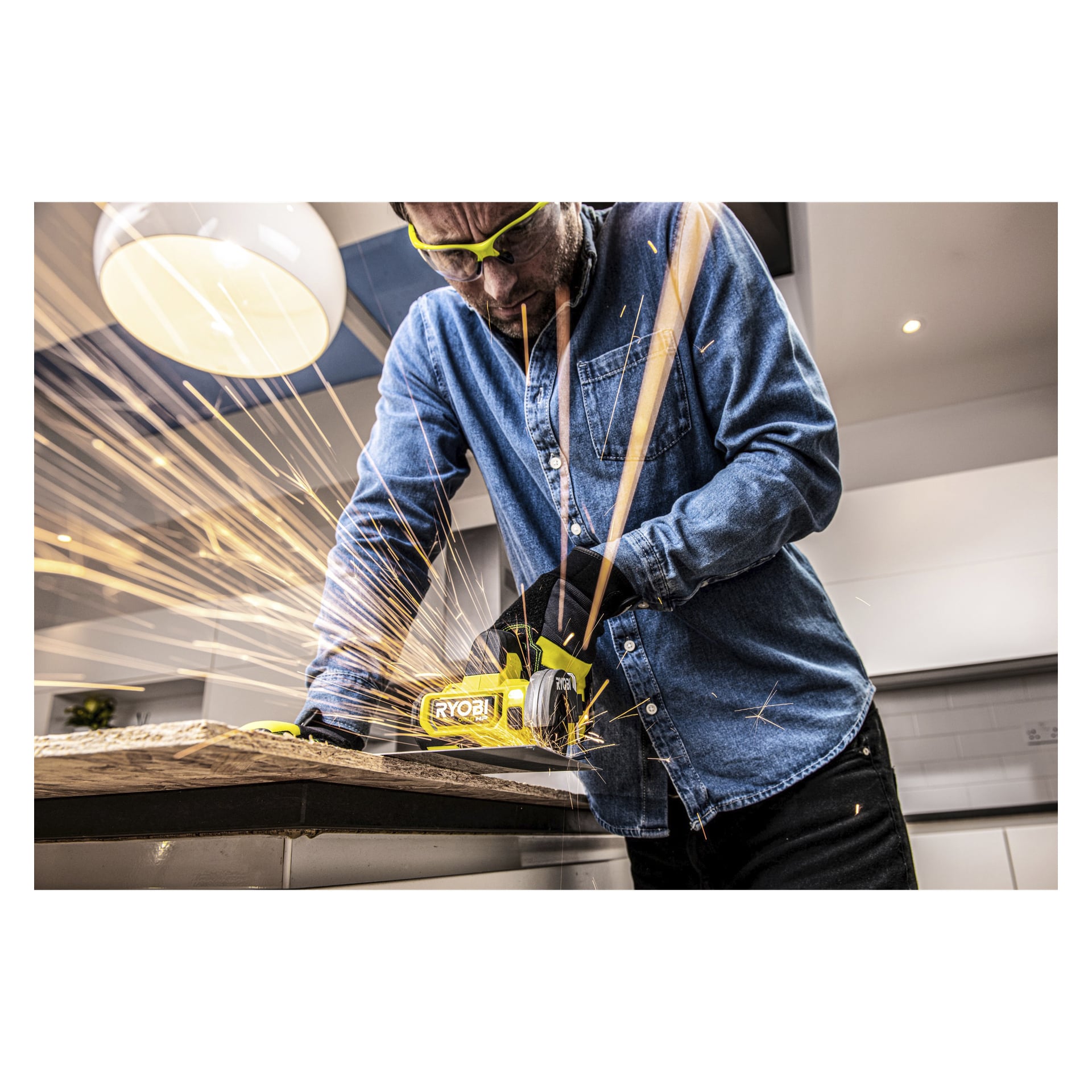 En person med vernebriller og hansker bruker en Ryobi One+ HP Cutter RCT18C-0 på en treplate, og sender lyse gnister i et lyst, moderne innendørs verksted.