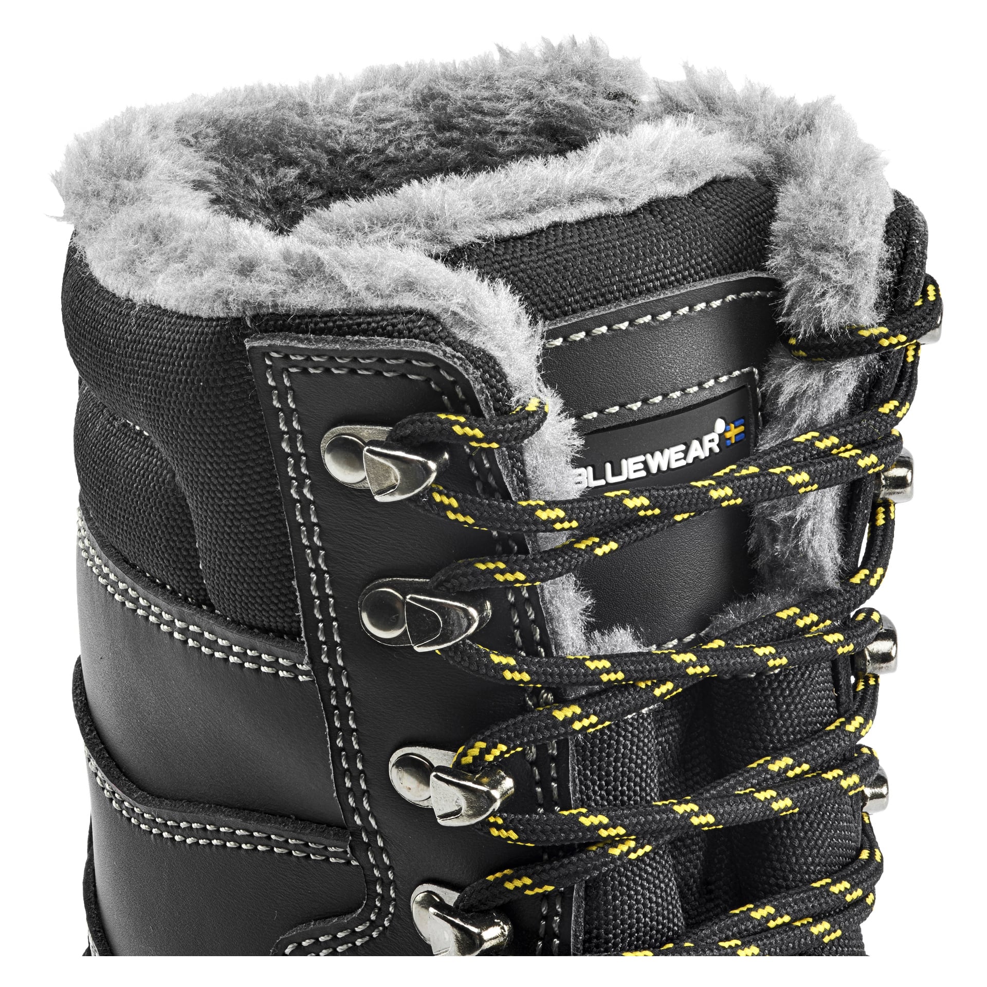 Närbild av en svart Bluewear GRIP säkerhetsstövel med varm foder, detaljerad med gula och svarta snören som löper genom metallöglor, vita sömdetaljer och grå fuskpäls på insidan. En Bluewear-etikett syns nära översidan av stöveln.