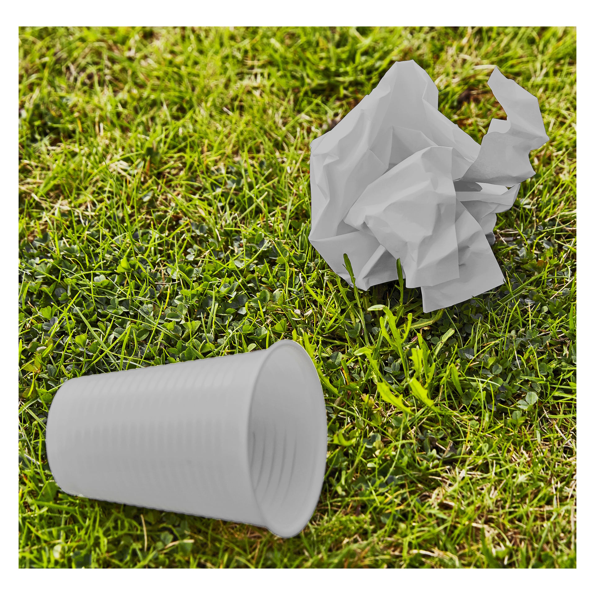 Na bujnej trawie obok białego plastikowego kubka i pogniecionej kartki białego papieru stoi Hard Head Dumpbish Picker.