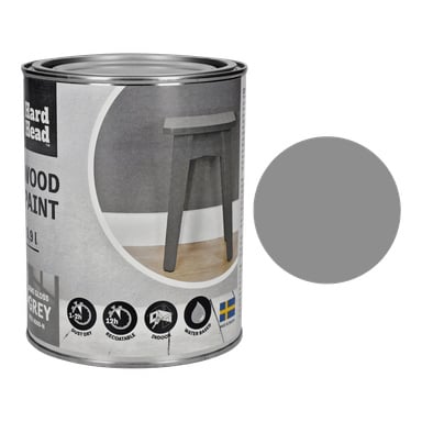 En boks med Hard Head Wood-maling i myk blank grå, med en etikett som viser en liten grå krakk, fremhevede detaljer og et bilde av det svenske flagget. En helgrå malingsprøve plasseres ved siden av boksen for å vise fargen.