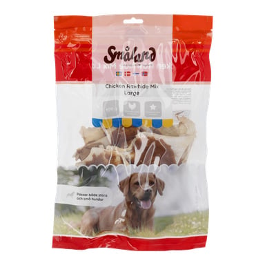 En genomskinlig plastpåse med Småland Chewing Bone hundgodis med olika råhudsbitar, med en brun hund liggande på gräs och produkttext.