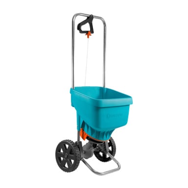 En blå og grå Gardena Universal Spreader med et solid metallhåndtak, svarte hjul og en oransje justeringsknapp. Sprederen har en rektangulær beholder med en stor åpen topp for enkel fylling, og er ment for å spre plenpleiematerialer.