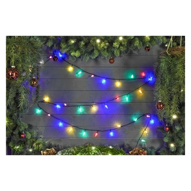 EKVIP:s flerfärgade LED-ljusslingor är arrangerade längs mörka träpaneler, dekorerade med tallgirlander och bruna ornament. De runda LED-lamporna lyser med ett mjukt, varmt ljus och ger scenen en festlig och mysig julkänsla.