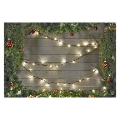 En trävägg prydd med EKVIP LED-ljusslingor från Connectable System, draperad med gröna tallgirlanger och dekorerad med röda och gyllene julkulor inbäddade bland lövverket.