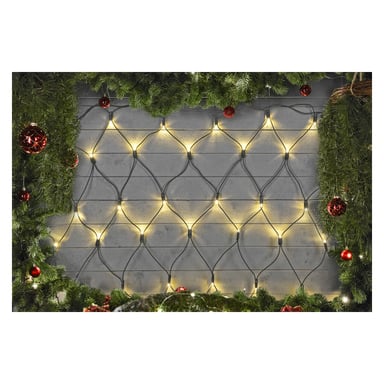 Gula LED-lampor från EKVIP Connectable System bildar ett lysande nät över en trävägg. Scenen ramas in längs toppen och sidorna av gröna tallgrenar och röda julgransprydnader, vilket ger den ett glatt julintryck.