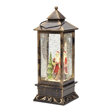 EKVIP Luminous LED-tomtelampa visas som en vintagelykta med guldfärgad exteriör, klara glassidor och ett svart handtag på toppen. Inuti finns två tomtefigurer och en grön julgran, med glitter som virvlar runt för att efterlikna snöfall.