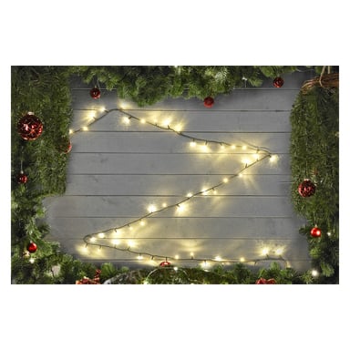 EKVIP LED-lysslynger er arrangert i et sikksakkmønster på en grå trevegg, og skaper en treform omkranset av furugrener og røde ornamenter for et festlig julepreg.