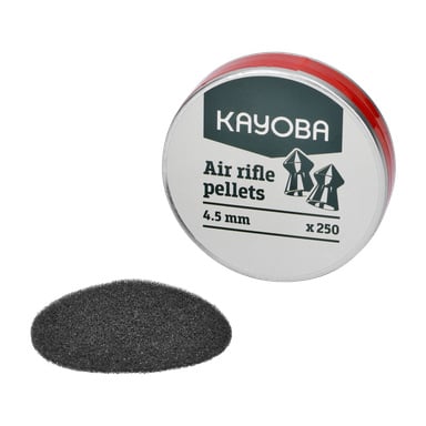 En rund burk märkt "Kayoba Air rifle pellets 250 pack" placeras bredvid en liten hög med mörka kulor. Plåten har en övervägande vit färg, accentuerad med röd kant och gröna bokstäver.