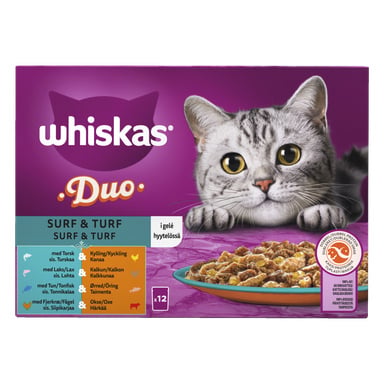 En Whiskas Cat Food 1+ Surf & Turf 12-pack låda visar en grå tabbykatt som tittar på en tallrik mat. Förpackningen lyfter fram "Surf & Turf"-varianten och visar olika smaker. Bakgrunden är lila med orange detaljer.