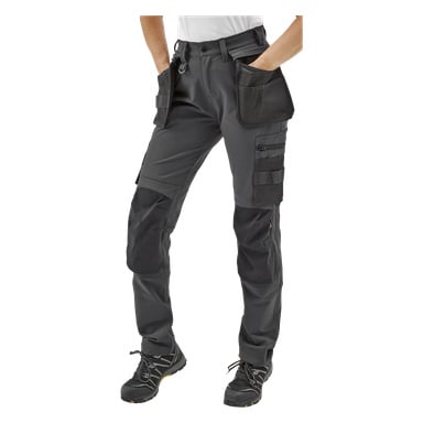 En person i Bluewear Pro Workwear Women's work pants Stella med flera fickor och förstärkta knän, svarta arbetsskor, endast underkroppen synlig och händerna instoppade i fickorna.