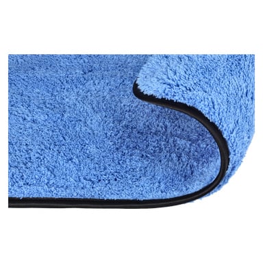 Närbild på det blå Hamron Microfiber-tyget med ena hörnet vikt, vilket visar dess mjuka, fluffiga textur och svarta broderade kant.
