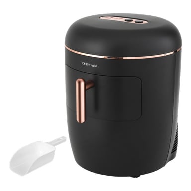 En matt svart sylindrisk Bright-ismaskin med roségulldetaljer og et håndtak er plassert ved siden av en hvit plastscoop. Tre kontrollknapper er plassert øverst, og Bright-logoen vises tydelig på forsiden av apparatet.
