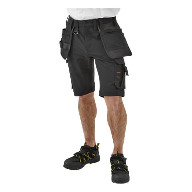En person vises fra livet og ned, kledd i Bluewear Pro Workwear Men's Steve svarte arbeidsshorts med flere lommer og løkker, kombinert med svarte arbeidssko med gule detaljer. Overkroppen er utenfor rammen.