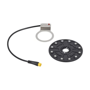 Ett elcykelkit med vevaxelsensor med sensor och svart sensorskiva, kabel med gul kontakt och metallring med fäste.