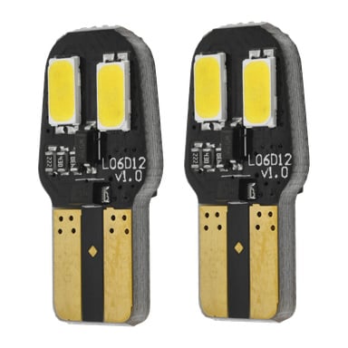 Två identiska Hamron LED-billampor (W5W 2-pack) med små svarta kretskort har gula rektangulära ljussändare, guldkontakter och text som märker dem som "L06D12 v1.0." Korten har synliga elektroniska komponenter.