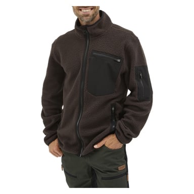 En man ler med ena handen i fickan, klädd i Kayoba Outdoor Men's pile jacket Ljusdal – en mörkbrun fleecejacka med dragkedja och svarta fickor med dragkedja på bröst och ärm. Han kombinerar den med mörkgröna byxor med svarta dragkedjedetaljer.