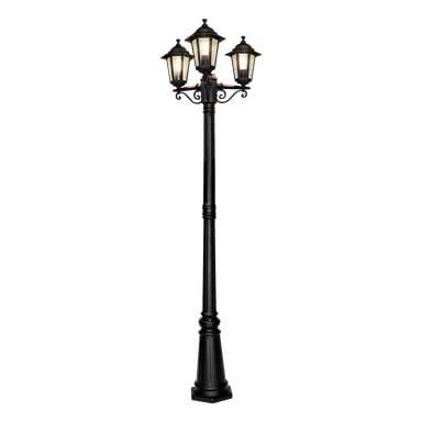 Latarnia Black Anslut na zewnątrz z trzema lampami w stylu latarni, każda wyposażona w matowe szklane panele. Ozdobne zdobienia zdobią przestrzeń pod lampionami, a podstawa jest solidna i żłobkowana. Wszystkie trzy światła są włączone.