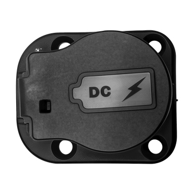 Närbild på ett svart laddningsportslock med en silveretikett som visar "DC" och en blixt, med skruvhål i varje hörn.