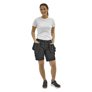 Personen står framåt i en vit t-shirt, svarta cargoshorts och svarta sneakers med orange detaljer; Händerna i fickorna.