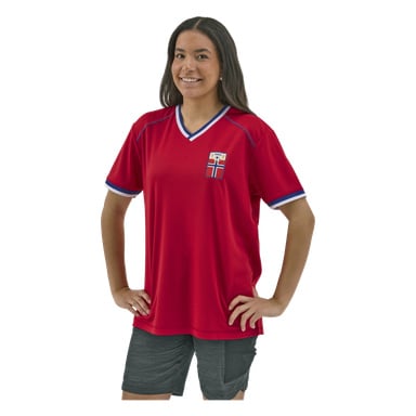 En person med langt mørkt hår bærer en rød sportsdrakt med blå og hvit kant, et norsk flaggmerke og mørke shorts, og smiler selvsikkert.