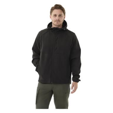 Nainen katsoo eteenpäin, pukeutuneena Kayoba Outdoor Women's -fleecevuorattuun pehmeäkuoriseen takkiin Hede mustiin ja oliivinvihreisiin housuihin. Hänen vasen kätensä lepää taskussa ja oikea käsi roikkuu sivulla.
