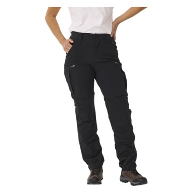 Osoba ubrana w biały T-shirt, brązowe buty trekkingowe oraz damskie spodnie Kayoba Outdoor Abisko z nogawkami na zamysek. Spodnie mają kieszenie na zamek i można je zamienić w szorty. Prawa ręka jest na biodrze, a lewa ręka jest zgięta i niewidoczna na zdjęciu.