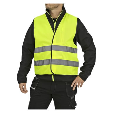 Eine Person in schwarzer Kleidung trägt ein Bluewear Reflective Tabard, eine leuchtend gelbe Sicherheitsweste mit zwei horizontalen reflektierenden Streifen. Sie haben eine Hand in die Hüfte gestemmt und das Gesicht teilweise von der Kamera abgewandt.
