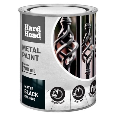 En 700 ml boks med Hard Head Metal-maling i matt svart (RAL 9005), med en etikett med bilder av dekorativt metallarbeid og tekst inkludert tørketid, omlakkering etterpå, samt for innendørs og utendørs bruk.