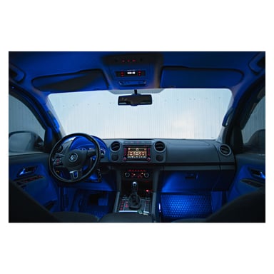 Volkswagenin sisällä kojelauta, ohjauspyörä, keskikonsoli ja etupenkit ovat Hamron Music Controlled LED Strips 4 Packin sinisen hehkun valossa. Pysäköity auto katsoo aaltopeltiseinää vasten.