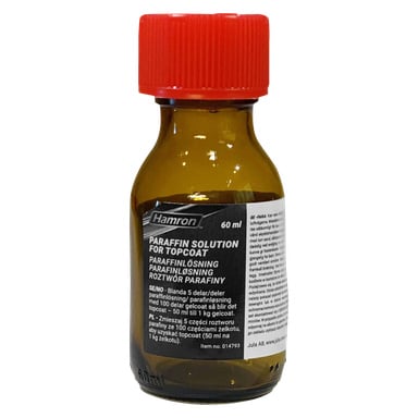 En liten bärnstensfärgad glasflaska med röd kork, märkt "Hamron Paraffin Solution" (60 ml). Etiketten visar bruksanvisningar.