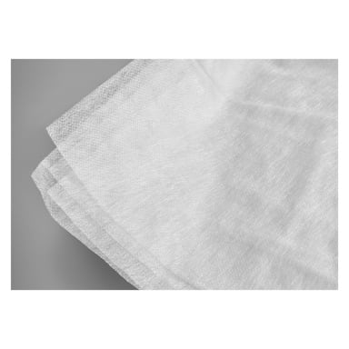 Flera tunna, texturerade ark av Hard Head Fiber-tyg överlappar varandra på en grå yta, deras något genomskinliga, icke-vävda material tydligt synligt.