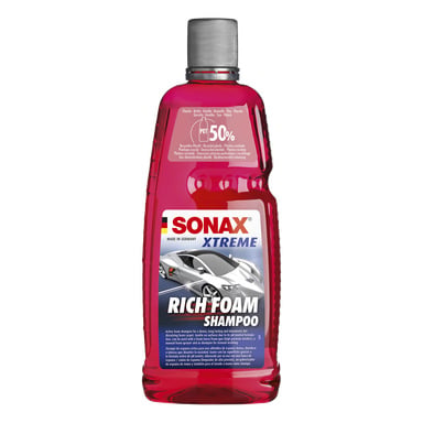 En klar plastflaska med röd vätska, Sonax Car Shampoo-etikett, silverlock och en sportbilsgrafik; märkt som tillverkat i Tyskland.